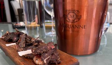 A close-up of a tray with food in front of a wine estate ice bucket.