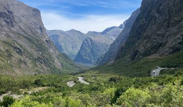 Scenic road winding through lush valley and mountains.