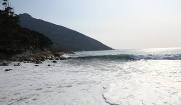 Waves crashing on a rocky shore with a mountain in the background.