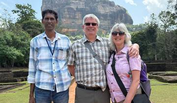 Three people posing in front of the rock fortress with greenery.