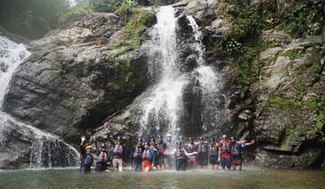 People enjoying a waterfall dressed in life jackets and helmets.