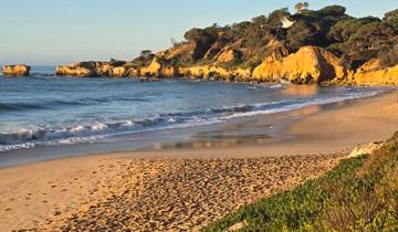 Beach with golden sand and cliffs at sunset.