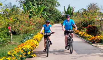 Two people biking on a scenic path lined with flowers.
