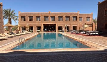 Luxurious hotel with a large pool and palm trees.