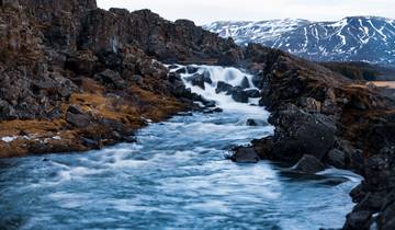 River flowing through a rocky landscape with snowy mountains in the distance.