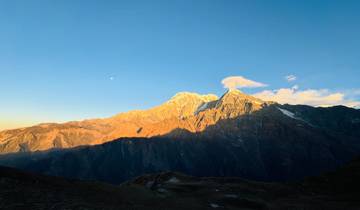 Sunlit mountains with a clear sky casting dark shadows.