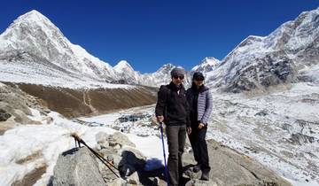 Two people in winter clothes on a snowy mountain path.