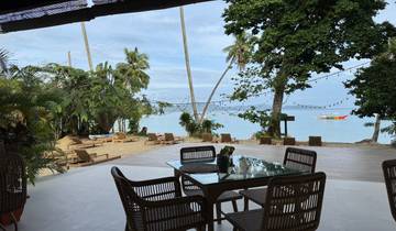 A beachside view with palm trees, sun loungers, and a clear sky.