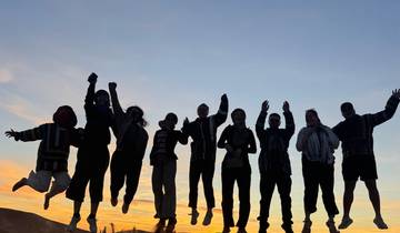 Silhouette of people jumping in the desert at sunset.