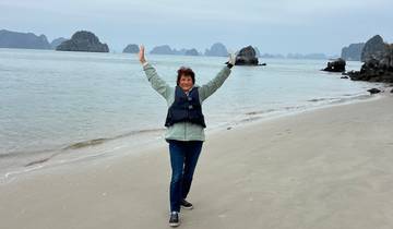 A person standing on a beach with sea stacks in the background.