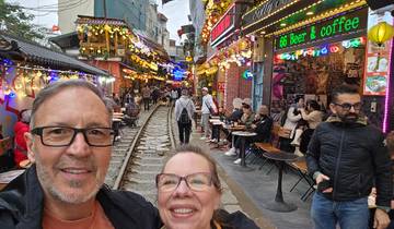 Lively street scene with railway and people dining at cafes.