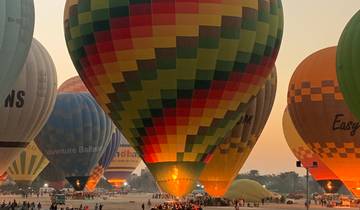 Colorful hot air balloons inflating on open land.