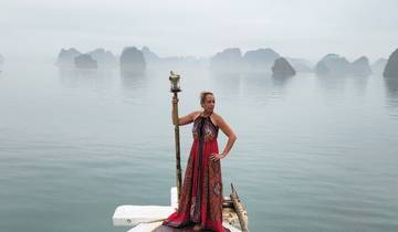 Woman in a fancy dress holding a torch with rocky islands behind.
