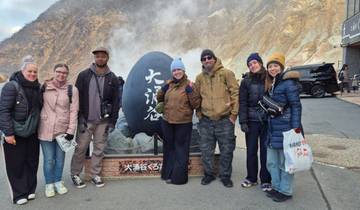 Group of people posing near a large rock with steam.