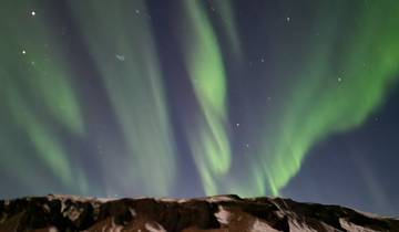 Northern lights over a snow-covered mountain.