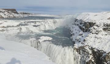 Snow-covered waterfall flowing into a river below.