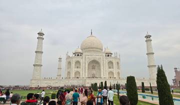 Front view of the Taj Mahal with crowds and gardens.