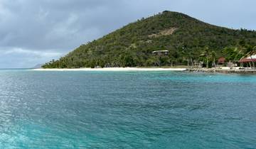 Beach with turquoise water and a hill in the background.