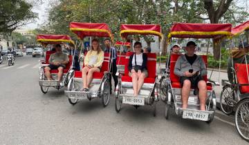 People sitting in red cycle rickshaws on a street.