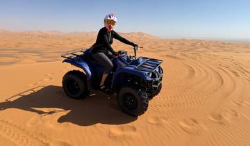 Person riding an ATV on sand dunes.