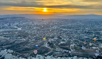 Aerial view of hot air balloons over Cappadocia at dawn.