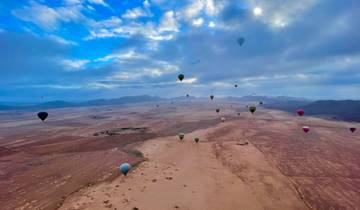 Hot air balloons soaring over a vast desert landscape.