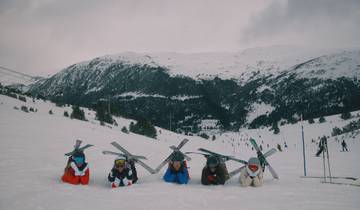 Group of people lying in the snow with skis.