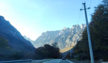 A car driving on a road surrounded by majestic mountains.