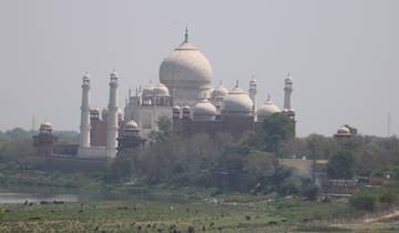 A distant view of the Taj Mahal across a river.