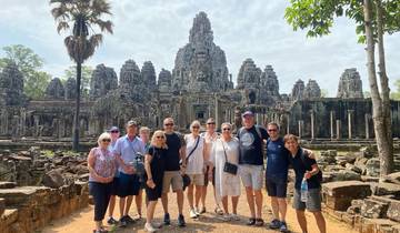 Group of tourists posing in front of Angkor Thom temple complex.