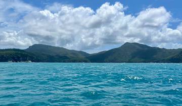 Ocean with waves and hills under a cloudy sky.