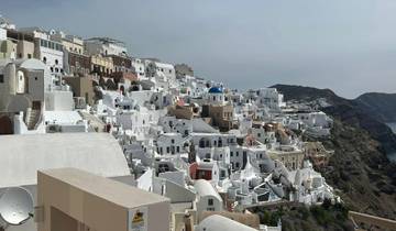 View of white buildings on a cliff with a blue dome.