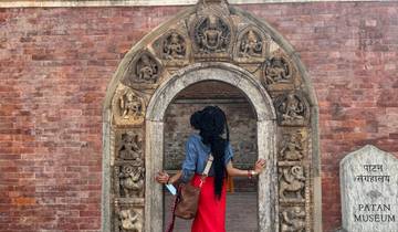 Person standing in front of an intricately carved doorway at Patan Museum.