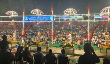 Evening ritual performance on a stage before a large crowd.