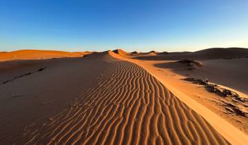 Extended sand dune landscape under a clear sky.