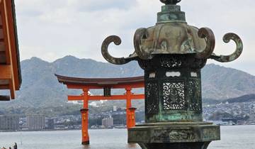 Traditional Japanese structure with water and mountains in the background.