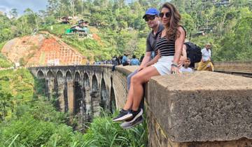 Couple sitting on a wall overlooking the Nine Arch Bridge.