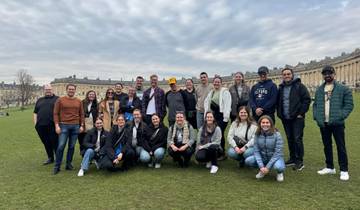 Large group of people posing in front of historic buildings.