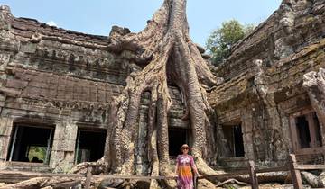 Person posing with a massive tree-rooted temple.