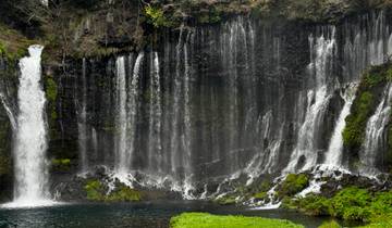 Waterfall cascading over dark rocks into a pond.