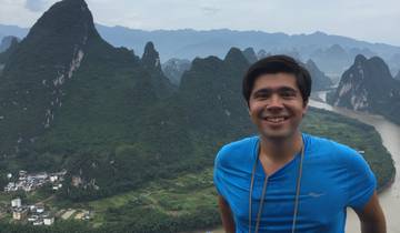A smiling man with scenic karst mountains in the background.