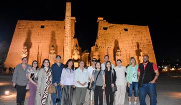 Group of people in front of a large illuminated temple at night.
