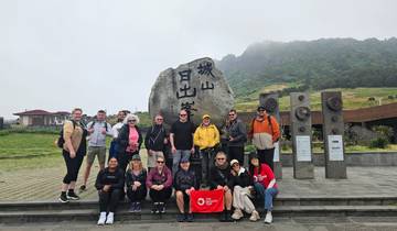Group of tourists posing in front of a rock with inscriptions.