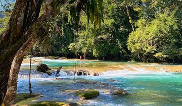Tropical waterfalls flowing over rocks with lush greenery.