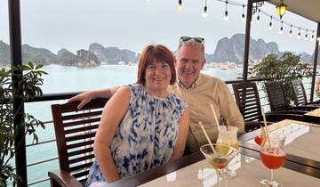 Couple relaxing at a waterside cafe with a view of limestone islands.