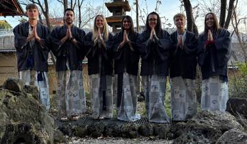 Group of people wearing traditional attire, standing in a garden area.