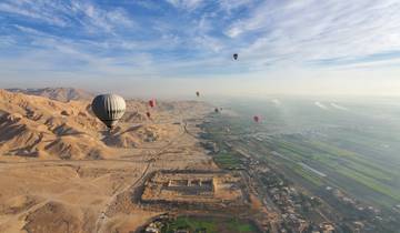Hot air balloons over desert and farmland.