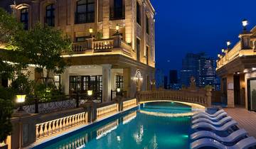 A luxurious hotel rooftop pool at night with city views.