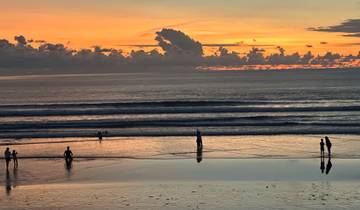 A scenic beach sunset with people walking on the shore.