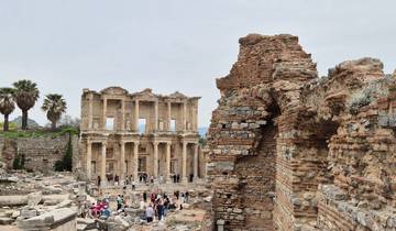 Archaeological ruins with a large structure in the background.
